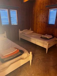 two beds in a room with two windows at Athens Palaia Fokaia Entire Flat 2 bedrooms with panoramic sea views and a massive veranda , only steps away from the beach and amenities in Palaiá Fókaia