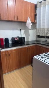 una cocina con armarios de madera y un aparato blanco en JB apartment, en Kisumu