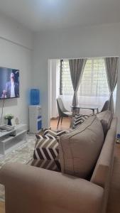 Una sala de estar con un sofá y un televisor. en JB apartment, en Kisumu