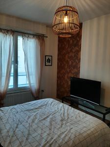 Schlafzimmer mit einem Bett, einem TV und einem Kronleuchter in der Unterkunft chambre dans maison place du commando, bord de mer in Saint-Nazaire