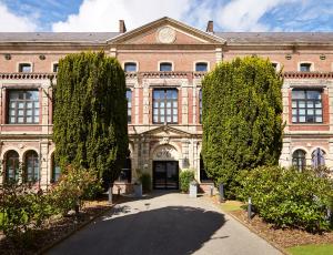 a large brick building with trees in front of it at Best Western Hôtel Hermitage in Montreuil-sur-Mer