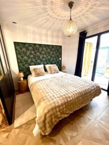 TréveneucにあるAu Ty Cocon,avec Jaccuzi privatif à 950 m de la plages et du GR34の大きなベッドとシャンデリアのある寝室