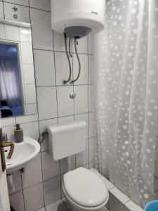 a white bathroom with a toilet and a sink at Apartmani Župa in Tivat