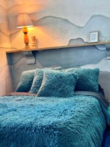 a bed with a blue blanket and a lamp on it at Casa Villa María, Recién Remodelada in Villa de Leyva