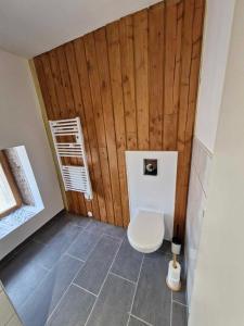 a bathroom with a toilet with a wooden wall at Maisonnette de la Butte de Thil in Nan-sous-Thil