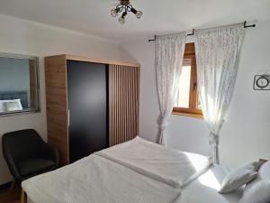 a bedroom with a bed and a chair and a window at Apartment Mija Rabac with free parking in a garage in Rabac