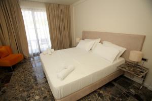 una camera da letto con un letto con lenzuola e cuscini bianchi di Durres Bay Hotel a Durrës