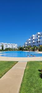 a large swimming pool with buildings in the background at Jawhara smir 2ET vue piscine in M'diq