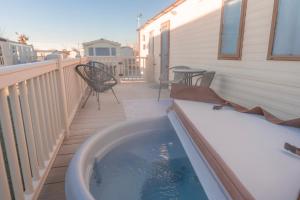 a hot tub on a deck with a table and chairs at Tattershall Lakes in Tattershall