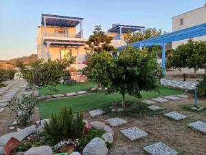 a house with a yard with trees and rocks at BLUE PARADISE SUITES in Pachaina