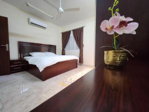a bedroom with a bed and a vase with flowers in it at iQama 2 in Salalah