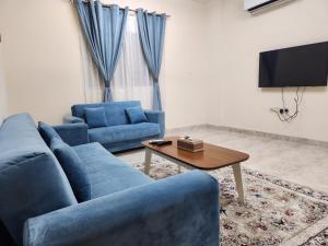 a living room with two blue couches and a table at iQama 2 in Salalah