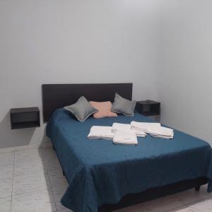 ein Bett mit blauer Bettwäsche und Handtüchern darauf in der Unterkunft Departamentos Falucho 3 in Santa Rosa