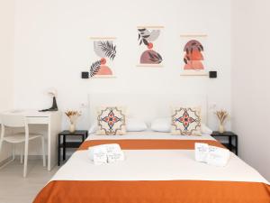 a bedroom with a bed with orange and white sheets and a desk at La Trinacria Rooms in Trapani
