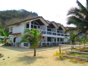 uma grande casa branca com uma palmeira em frente em Sundown Beach Hotel em Canoa