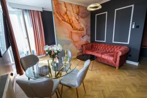 a living room with a red couch and a glass table at Allure GALAXY Centrum Aparthotel in Szczecin