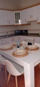 a white table with plates and wine glasses on it at GAVIOTA RELAX in Tarajalejo