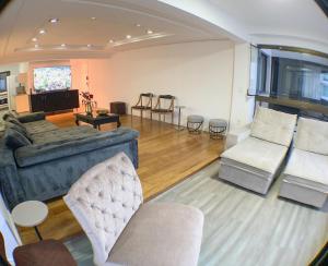 Una gran sala de estar con un sofá y sillas. en Frente mar, espaço e conforto, en Balneário Camboriú