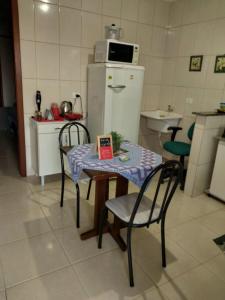 a small kitchen with a table and chairs and a refrigerator at Kit net 8 com ar condicionado cama Queen in Maringá