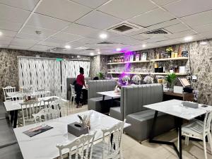 Ein Restaurant mit Tischen und Stühlen und einer Person im Hintergrund in der Unterkunft Bliss Square Hotel in Dubai