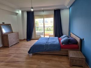 a bedroom with a bed with a blue wall at Villa avec piscine, Hacienda Beach Sidi Rahal in Sidi Rahal +17 photos