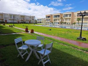 two chairs and a table in the grass with a building at Villa avec piscine, Hacienda Beach Sidi Rahal in Sidi Rahal