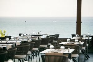 restauracja ze stołami i krzesłami z widokiem na ocean w tle w obiekcie KING MINOS RETREAT Resort & Spa w mieście Hersonissos