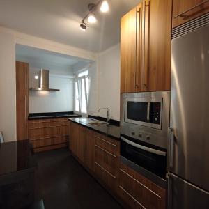 Una cocina con refrigerador de acero inoxidable y gabinetes de madera. en Quédate en casa Titi, en Santander