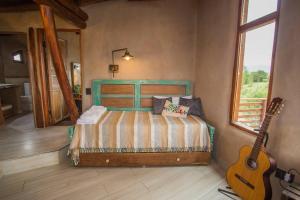 una camera da letto con un letto e una chitarra di Terracota Casa Eco Intiyaco Cordoba a Atos Pampa