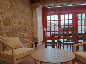 a living room with a table and chairs and a stone wall at Casa da Praza in Lobios
