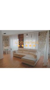 a living room with white couches and a stone wall at 300 mt from the Sea - Free Parking - Wi-fi AC & Prime Video in Lido di Camaiore