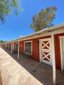 Joshua Tree Ranch House Motel - Downtown - Room #3 في جوشوا تري: حظيرة حمراء مع أبواب بيضاء وفناء