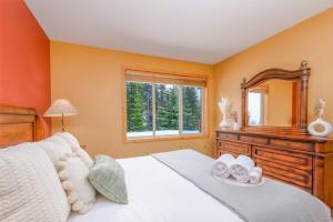 Un dormitorio con una cama con una cómoda y un espejo. en Best Ski-in out 3 Bdrm Chalet, with Hot Tub, en Big White 25 fotos más