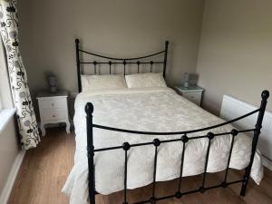 a bedroom with a black frame bed with white sheets at Keeranglen Holiday Rental in Pomeroy