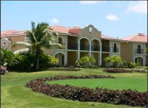 a large house with a palm tree in the yard at The Golf Suites in Punta Cana