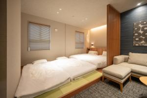 a bedroom with two beds and a chair and a couch at Hotel A'bant Shizuoka in Shizuoka