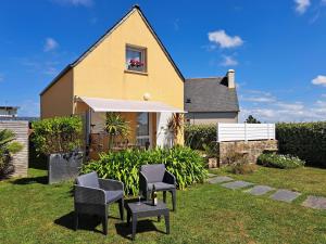 a house with two chairs and an umbrella in the yard at Cottage in Plouneour-Trez with Sea View in Plounéour-Trez