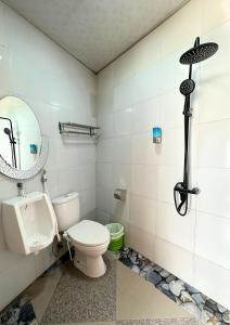 a bathroom with a toilet and a mirror at De Pointé Resort & Resto in Campaka
