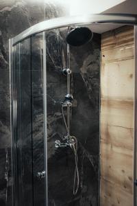 a shower in a bathroom with a black stone wall at Chałpa z bali in Zakopane