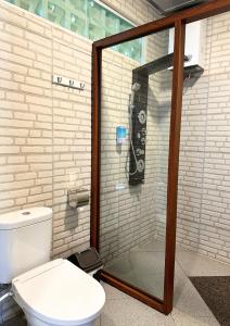 a bathroom with a glass shower with a toilet at De Pointé Resort & Resto in Campaka