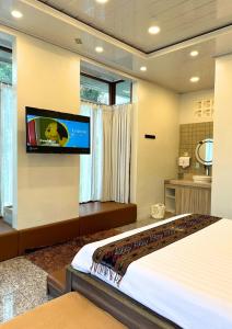 a bedroom with a bed and a flat screen tv on a wall at De Pointé Resort & Resto in Campaka