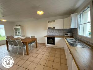 a kitchen with white cabinets and a wooden table at Maison rénovée 6 pers avec jardin, proche plages et pistes cyclables à Talmont-Saint-Hilaire - FR-1-426-557 in Talmont-Saint-Hilaire +8 photos