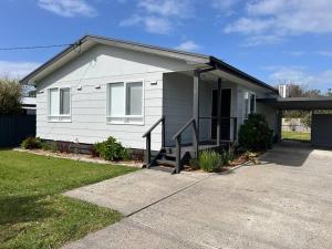 a white house with a porch and a driveway at Cowes Cosy Cottage in Phillip Island