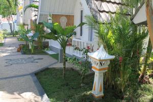 a garden with a bird house in front of a house at New Balengku Dua Hotel in Gili Air