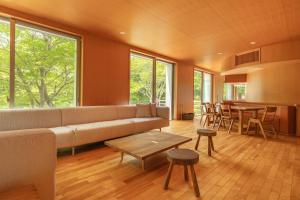 a living room with a couch and a table at NASU PRIVATE FOREST: 広大な森の中のモダンハウス in Shiozawa