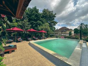 a swimming pool with chairs and red umbrellas at VILLA IPSA in Munduk