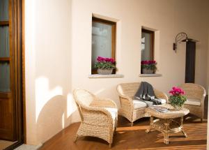 a porch with wicker chairs and a table and two windows at La Burla in Borgosesia