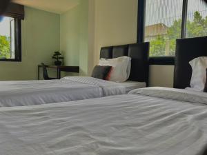 a room with two beds with white sheets and a window at Baan Ploy In in Chiang Mai