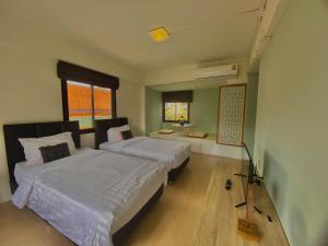 a bedroom with two beds and a desk in it at Baan Ploy In in Chiang Mai