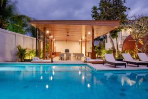 a swimming pool with chairs and a house at Ratan Uluwatu Hotel and Villas in Uluwatu